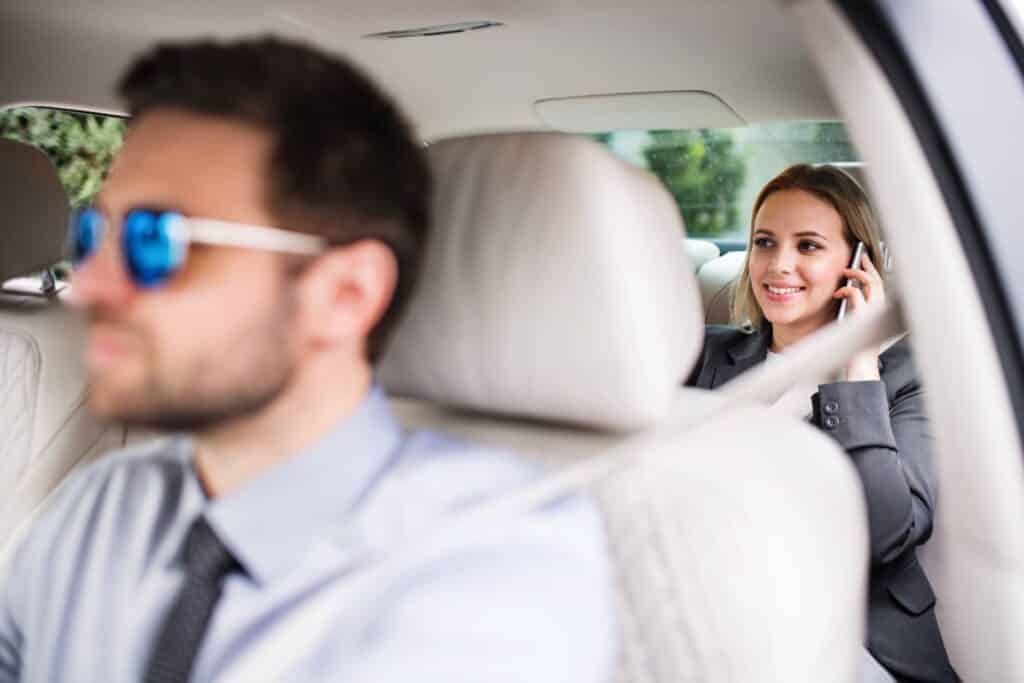 Business woman with smartphone sitting on back seats in taxi car, talking.