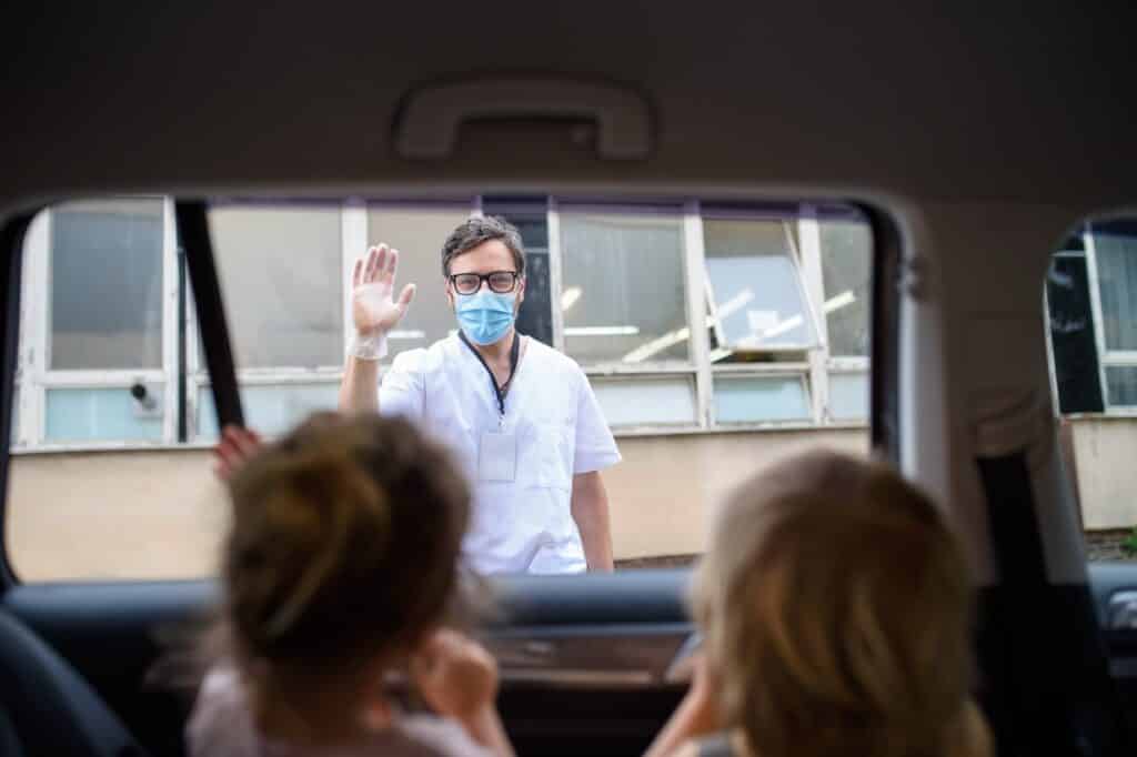 Doctor coming to see family in isolation, car window glass separating them.