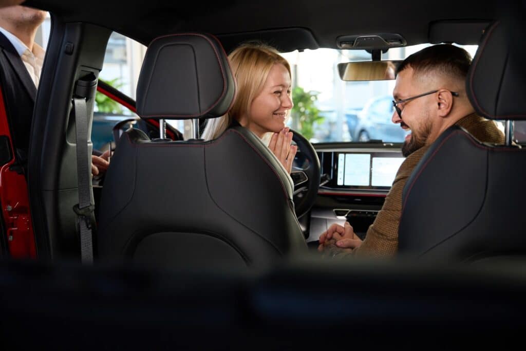 Young couple evaluates the interior of a new car