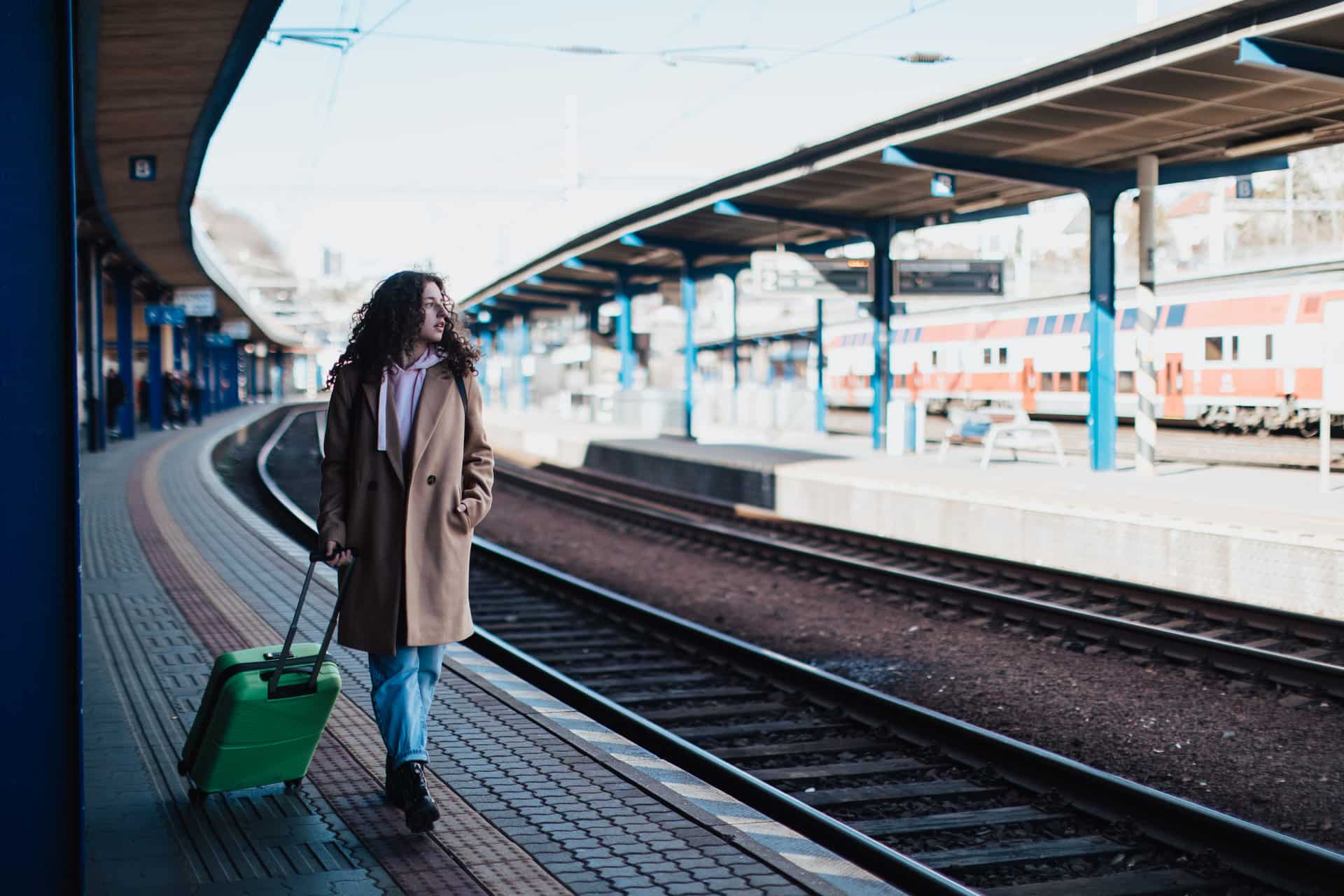 happy young traveler woman with luggage waiting
